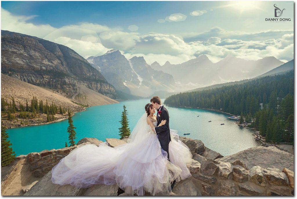 Couple walking through scenic Canadian landscape surrounded by pine trees and mountain peaks, perfect for destination wedding guests traveling to Canada.
