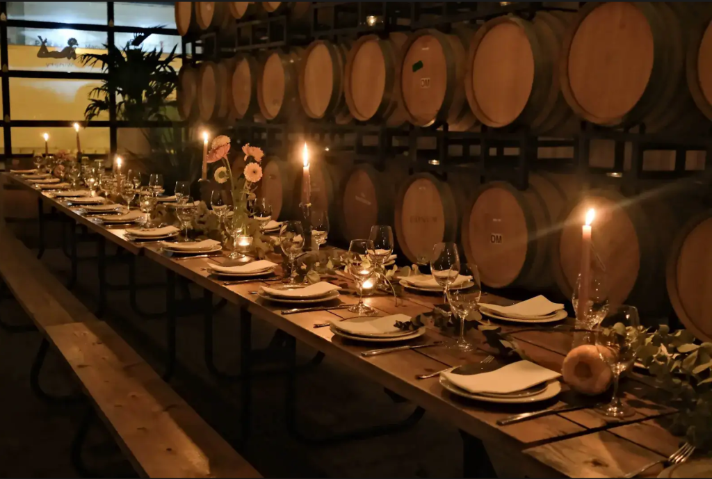 Candlelit wedding dinner setup inside a Toronto winery with wooden barrels and elegant table décor — intimate and stylish setting for unique destination weddings in Canada focused on wine, warmth, and celebration.