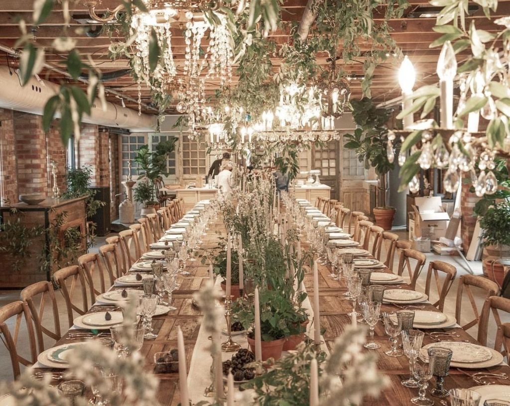 Elegant wedding reception setup at The Loft on King Street in downtown Toronto — long rustic tables, greenery, and chandeliers creating a modern yet timeless atmosphere for unique destination weddings in Canada.