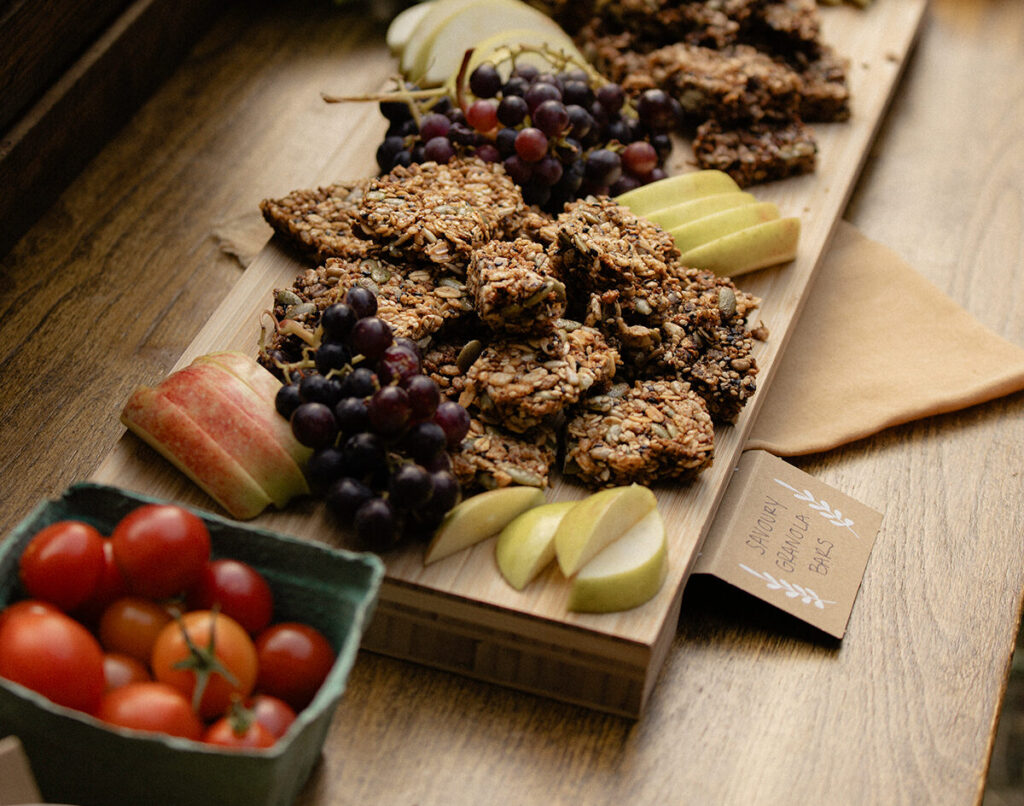 Vegan wedding catering graze board with savoury granola bars, fresh fruits, and tomatoes - Thistle and Thorne Weddings