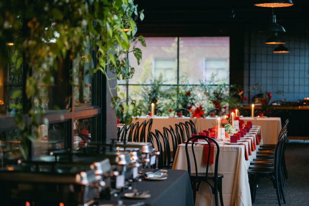 Sophisticated industrial-chic wedding reception table layout with red floral centerpieces - Thistle & Thorne