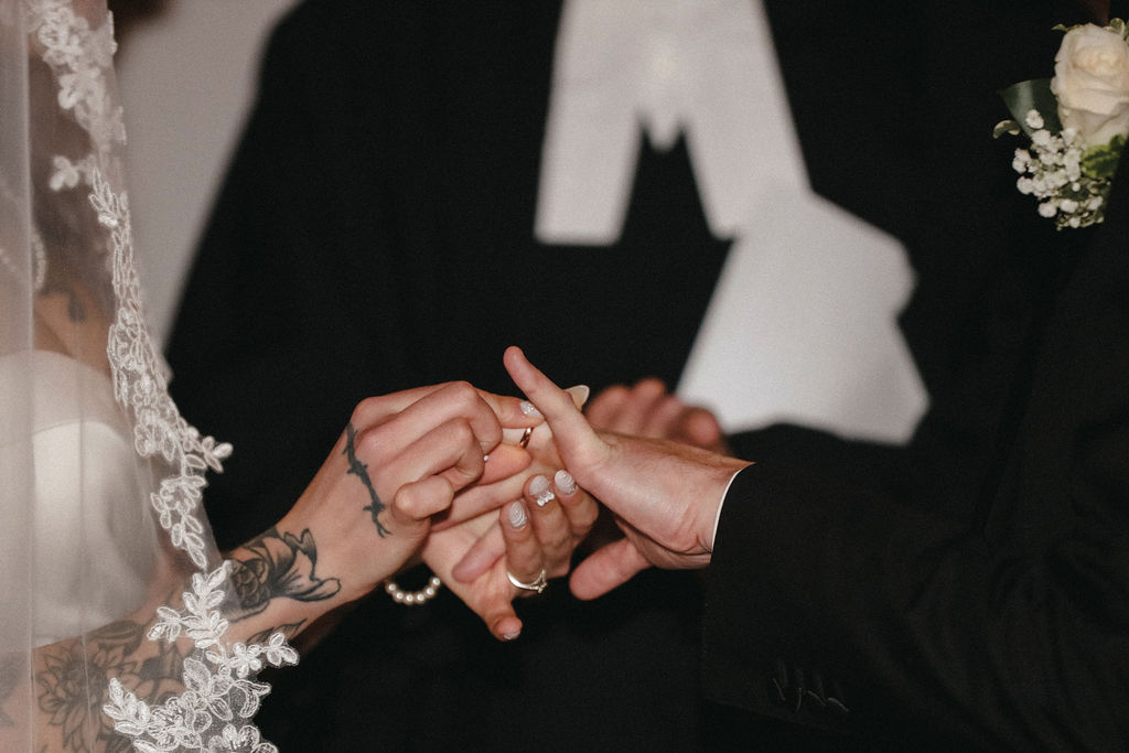 Close-up of Carl and Victoria exchanging wedding rings during their wedding ceremony.